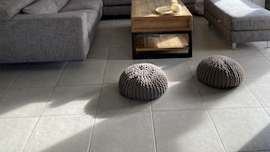 A modern living room with a sectional sofa, a wooden coffee table, and two poufs. - AIR-CONDITIONED VILLA WITH POOL AND SPA - GOLFE DE SAINT-TROPEZ (Le Plan-de-la-Tour)