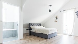 Un dormitorio moderno con cama, mesita de noche y ventana con cortinas.