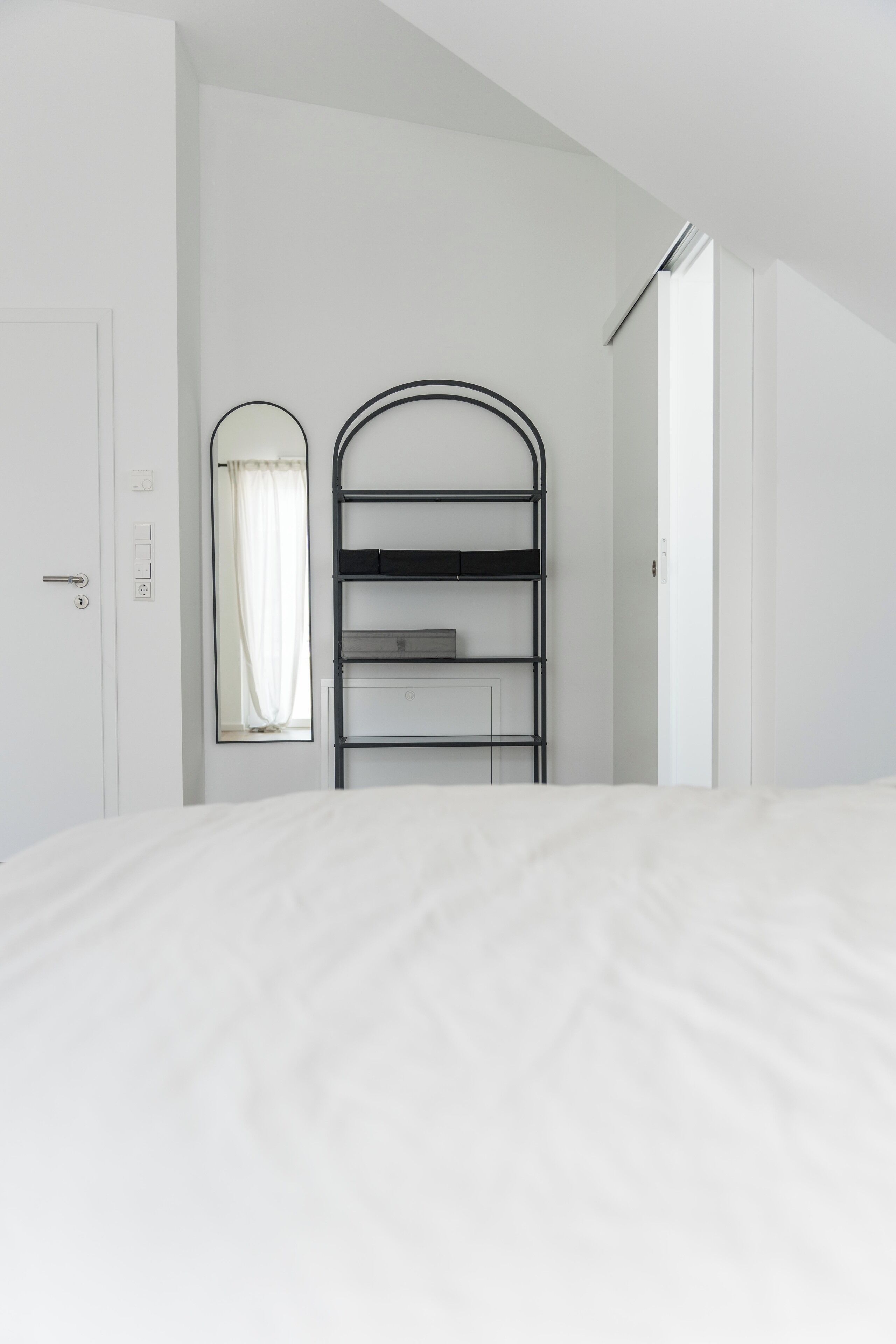 A minimalist bedroom with a bunk bed, a wardrobe, and a mirror.