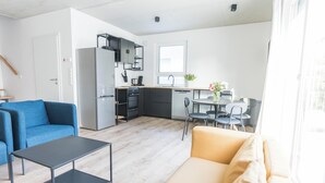 Un espacio habitable moderno con cocina, sofá, mesa de centro y comedor.