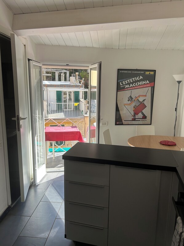 Une chambre d’hôtel dotée d’une porte-fenêtre coulissante donnant sur un balcon, d’une table en bois et d’une affiche accrochée au mur.