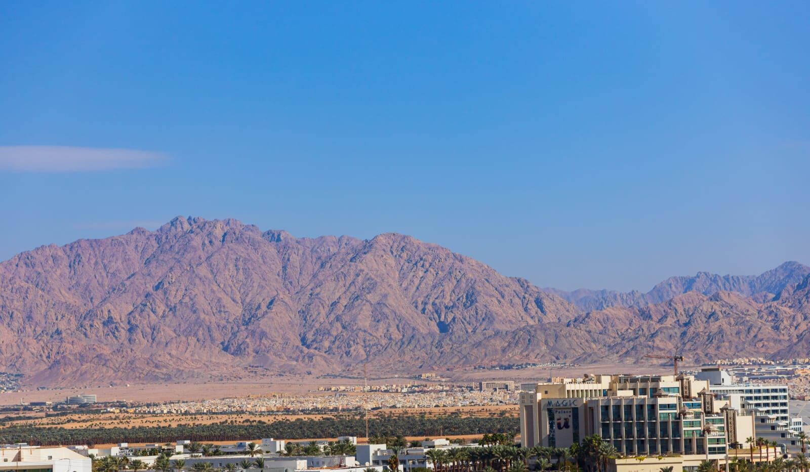 Une vue urbaine avec une chaîne de montagnes imposante en arrière-plan et des bâtiments modernes au premier plan.