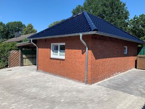 A brick building with a blue roof, a window, and a door. - Haus Seestern - Holiday home Seestern with modern furnishings and fenced garden (Cuxhaven)