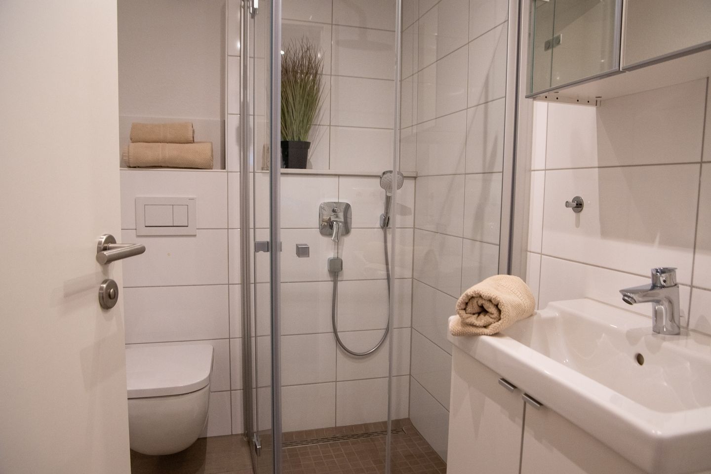 Ein modernes Badezimmer mit Duschkabine aus Glas, Toilette, Waschbecken und Handtuch.