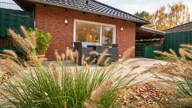A brick house with a tiled roof, a large window, and outdoor seating. - Haus Seestern - Holiday home Seestern with modern furnishings and fenced garden (Cuxhaven)
