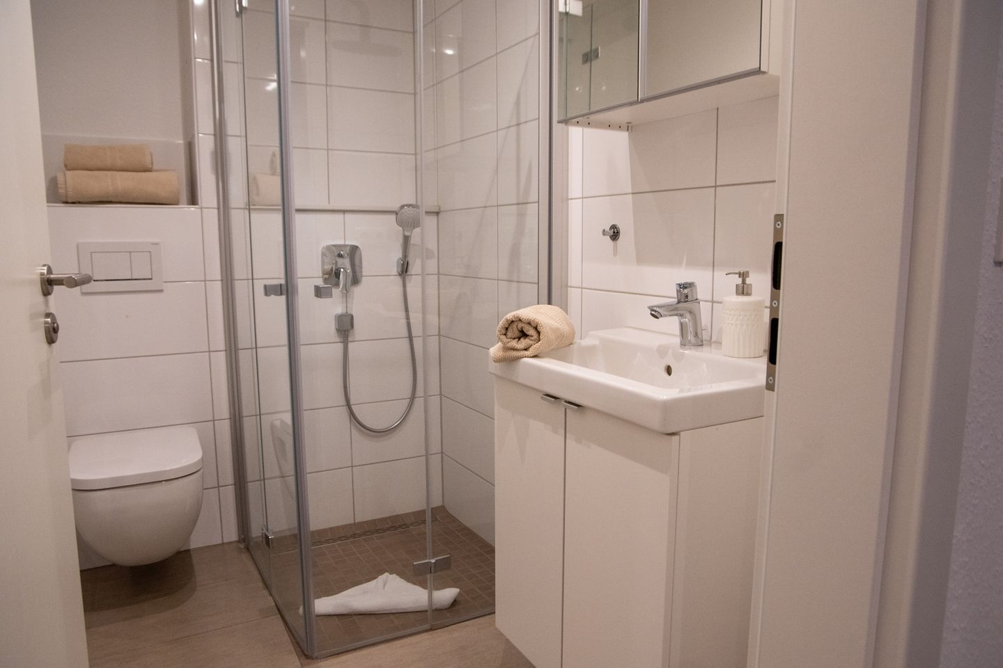 Ein modernes Badezimmer mit einer Duschkabine, einem weißen Waschbecken und einer Toilette.