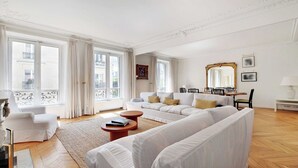 Een ruime woonkamer met een grote bank, een salontafel en een eethoek met stoelen en een tafel.