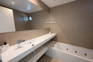 Une salle de bain moderne avec un grand miroir, un lavabo et une baignoire.