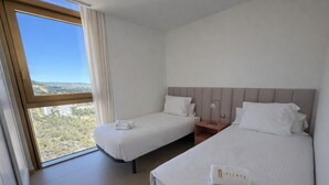 Ein Hotelzimmer mit zwei Betten, einem großen Fenster und Landschaftsblick sowie einem Nachttisch mit Lampe.
