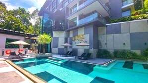 Ein modernes Gebäude mit Schwimmbad, Liegestühlen und Sonnenschirmen.