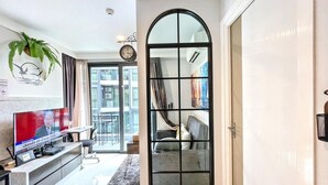 Ein modernes Wohnzimmer mit Fernseher, einer Couch, einem Essbereich und einem großen Fenster.