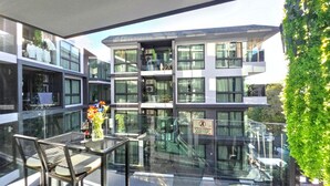 Ein modernes Gebäude mit mehreren Stockwerken, großen Fenstern und einem Glasgeländer, das auf einen Innenhof blickt.