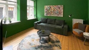 A living room with green walls, a grey sofa, a coffee table, and a painting on the wall.