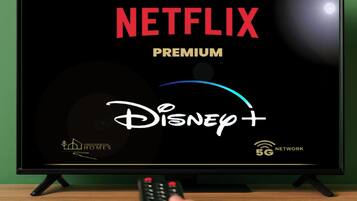 Un televisor mostrando la interfaz de Netflix Premium y Disney+ con un control remoto en la mano.