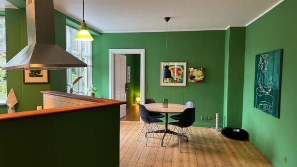 A dining area with a wooden floor, a table with chairs, and a hanging light fixture.