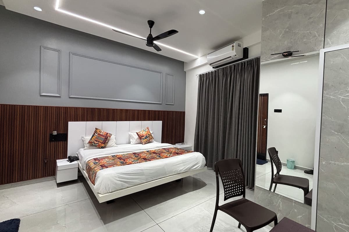 A modern bedroom with a bed, bedside tables, a chair, a ceiling fan, and a large mirror.