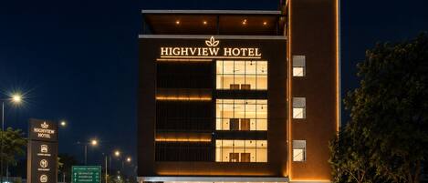 A modern hotel with a prominent sign, multiple floors, and a well-lit entrance.