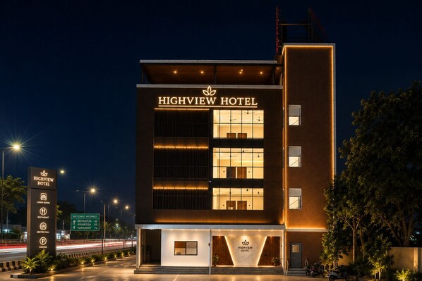 A modern hotel with a prominent sign, multiple floors, and a well-lit entrance.