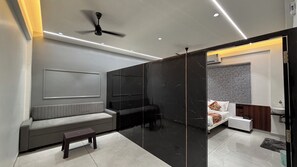 A modern living room with a sofa, a small table, a ceiling fan, and a black marble partition.