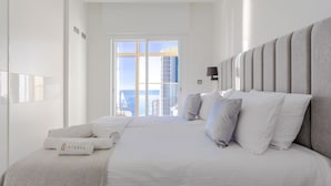 A modern hotel room with a large bed, a view of the ocean, and a cityscape in the background. - Intempo by Holuxe - 095 - 9th floor (Benidorm)