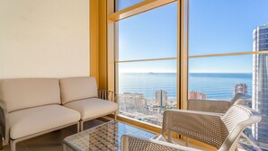 A room with a sofa and two chairs near a large window overlooking a city and the sea. - Intempo by Holuxe - 095 - 9th floor (Benidorm)