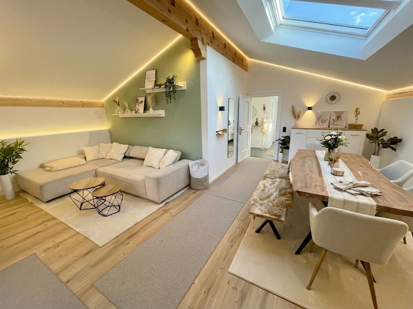 A modern living room with a sofa, dining table, and chairs. There is a skylight above the dining area. - Scandinavian Alpine Lodge - stylish & quiet in a top location near Tegernsee (Reichersbeuern)