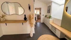 Een modern interieur met een houten console, een grote spiegel en een bankje.