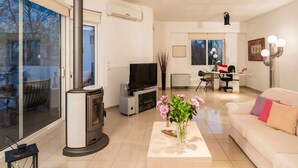 Ein modernes Wohnzimmer mit Kamin, Fernseher, Essbereich und Sofa.