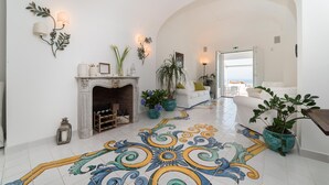 A spacious lobby with a tiled floor, a fireplace, potted plants, and a white sofa. - Art & Sea Boutique Villa (Praiano)
