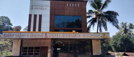 A hotel with a modern design, featuring a signboard for 'Hotel Lodging & Boarding' and a satellite dish on the roof.