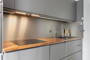 Una cocina moderna con encimera de madera, electrodomésticos de acero inoxidable y armarios grises.