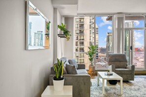 Ein modernes Wohnzimmer mit einer Couch, Sesseln, einem Couchtisch und Zimmerpflanzen.