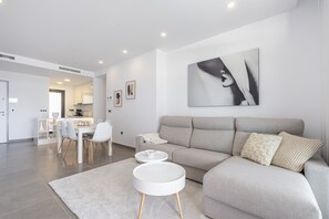 A modern living room with a grey sofa, a round white coffee table, and a large abstract painting on the wall. - Sunset Waves by Holuxe - 190 (Benidorm)