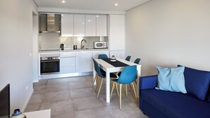 Una cocina moderna con armarios blancos, una mesa de comedor con sillas azules y un sofá azul con un cojín azul claro.