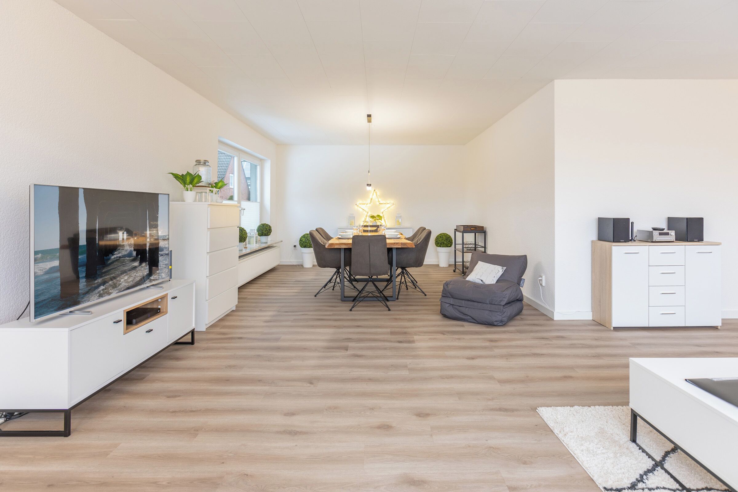 A modern living room with a dining area, a TV, and a cozy seating area.