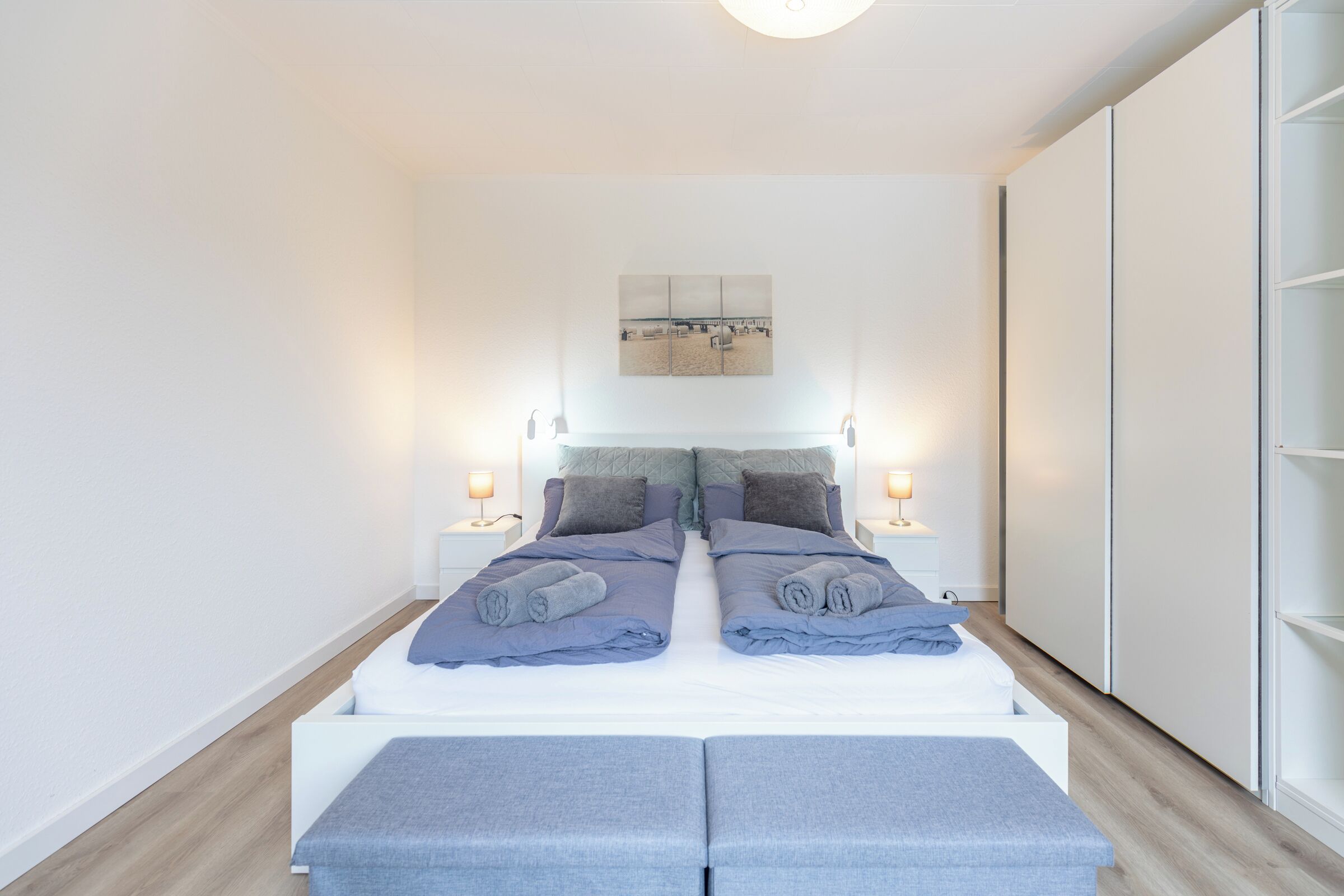 Ein modernes Schlafzimmer mit einem großen Bett, Nachttischen, einer Kopfteil und einem Kleiderschrank.
