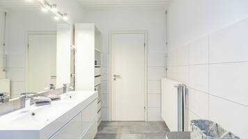 A modern bathroom with a white vanity, a large mirror, and a door.