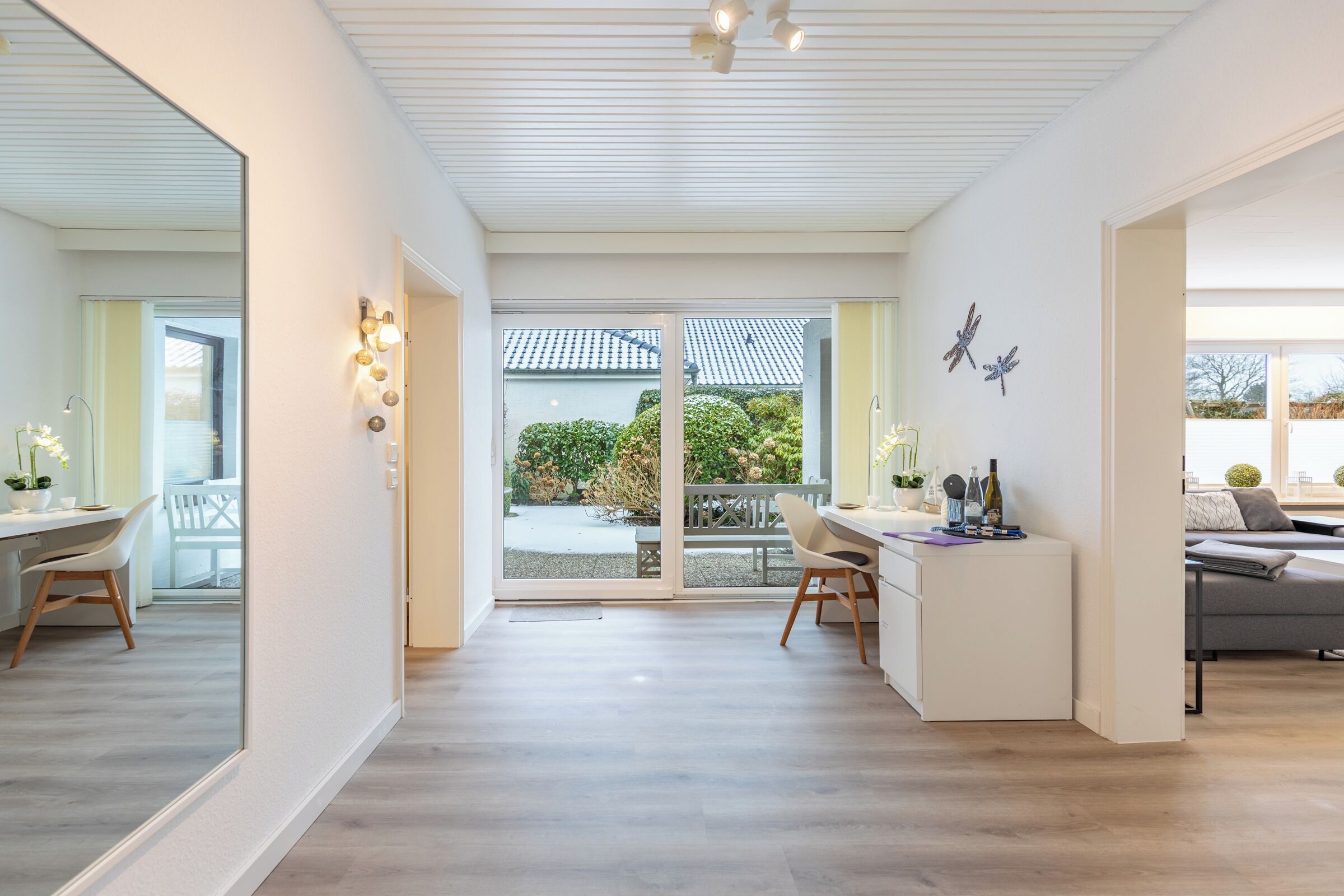 Un vaste espace de vie comprenant un grand salon avec une grande porte-fenêtre coulissante donnant sur un balcon, un coin repas avec une table et des chaises, et un espace détente avec un canapé et une table basse.