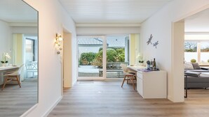 Amplia sala de estar con un gran ventanal corredera que da a un balcón, comedor con mesa y sillas, y zona de estar con sofá y una mesita de centro.