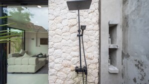 A modern bathroom with a stone wall, a freestanding shower, and a built-in shelf. - Bohemia Villa by Betterplace (Canggu)