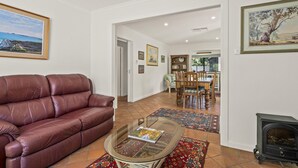 Uma sala de estar com sofá de couro, mesa de centro de vidro, tapete estampado e lareira.