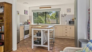 Uma cozinha compacta com uma ilha central, fogão e geladeira.