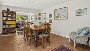 Uma sala de jantar com uma mesa e cadeiras de madeira, uma estante e um sofá.