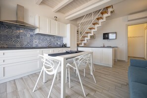 A modern kitchen with white cabinetry, a blue and white tiled backsplash, and a wooden staircase leading to a living area. - Apartment Lights (Avola)