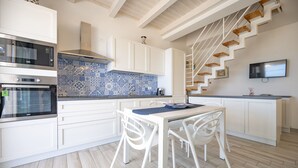 A modern kitchen with white cabinets, a blue patterned backsplash, and a wooden staircase. - Apartment Lights (Avola)
