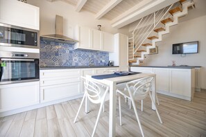 A modern kitchen with white cabinets, a blue patterned backsplash, and a wooden staircase. - Apartment Lights (Avola)