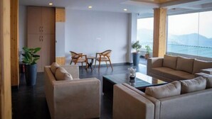 A modern living room with a sofa, chairs, a coffee table, and a view of the outdoors. - Hardys Retreat (Shimla)