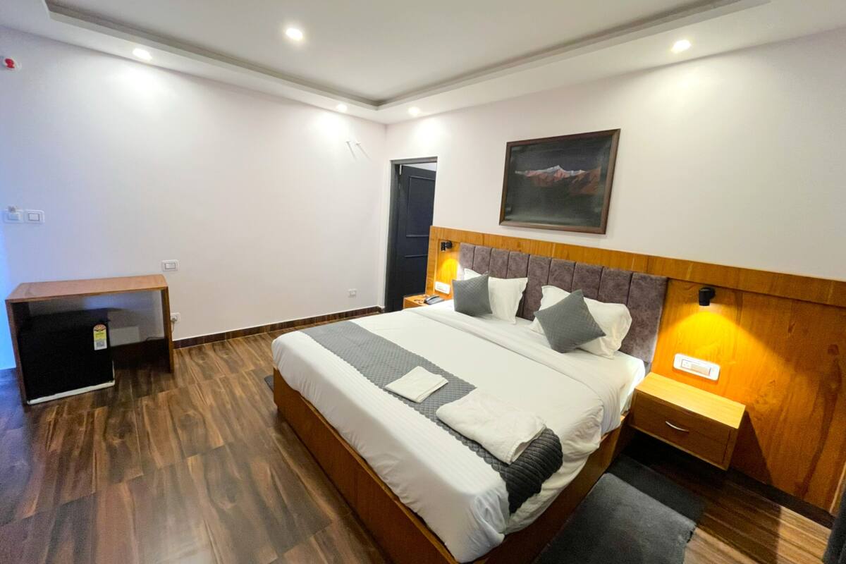 A modern bedroom with a large bed, bedside tables, a desk, and a door.