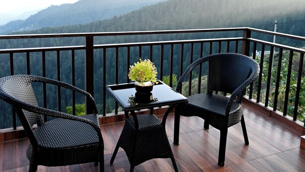 A balcony with two wicker chairs, a small table, and a potted plant. - Hardys Retreat (Shimla)