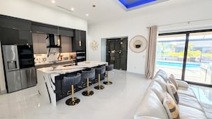Een moderne keuken met een centraal eiland, barstoelen en een eethoek.